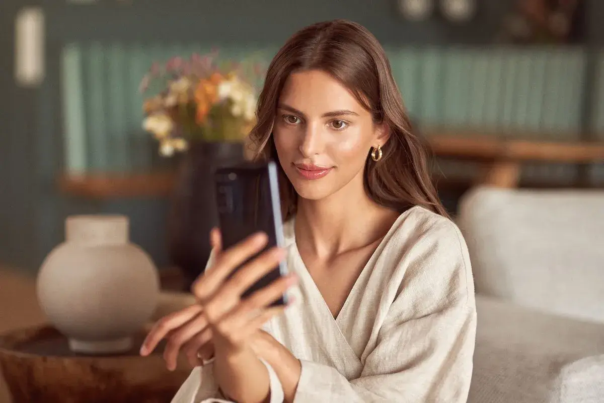 Kobieta robi selfie w lustrze, ale jej twarz jest zasłonięta przez telefon.
