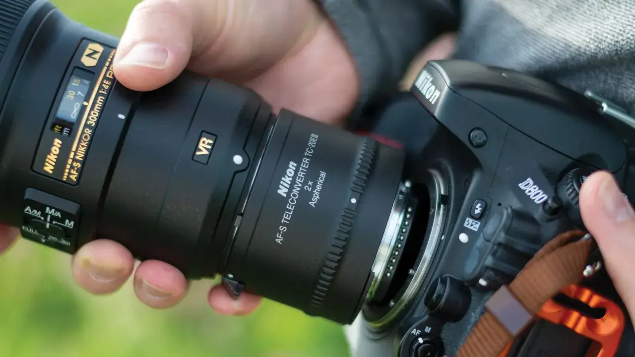 Dłonie trzymają aparat Nikon D800 z telekonwerterem AF-S TC-20E i obiektywem AF-S NIKKOR 300mm.
