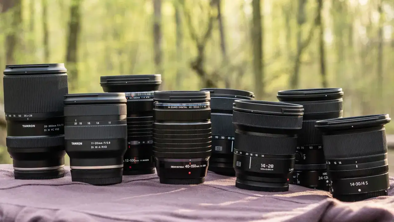Wybór, jaki obiektyw do krajobrazu? Na stole leży kolekcja obiektywów fotograficznych, od szerokokątnych po teleobiektywy, gotowych do uchwycenia piękna natury.