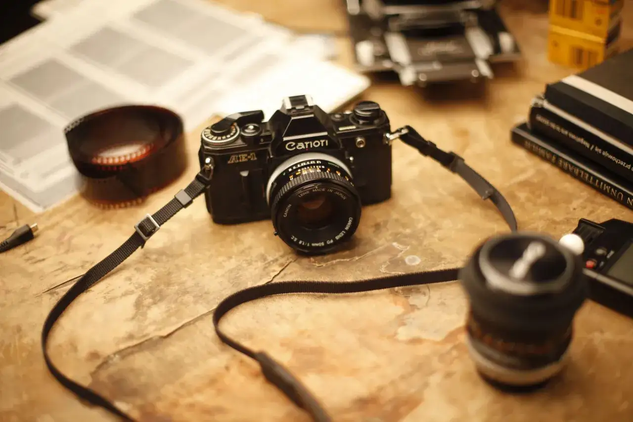 Stary aparat Canon AE-1, rolka kliszy i książki o fotografii. Idealny zestaw na kurs fotografii.