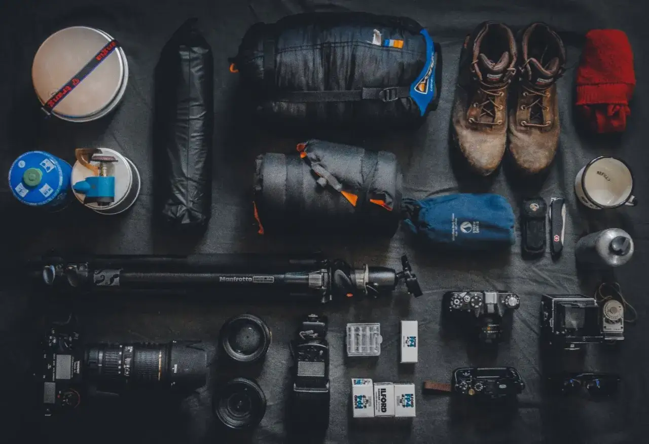 Sprzęt do fotografii podróżniczej: śpiwór, buty, aparat, obiektywy, statyw, kubek, termos, scyzoryk, filmy.
