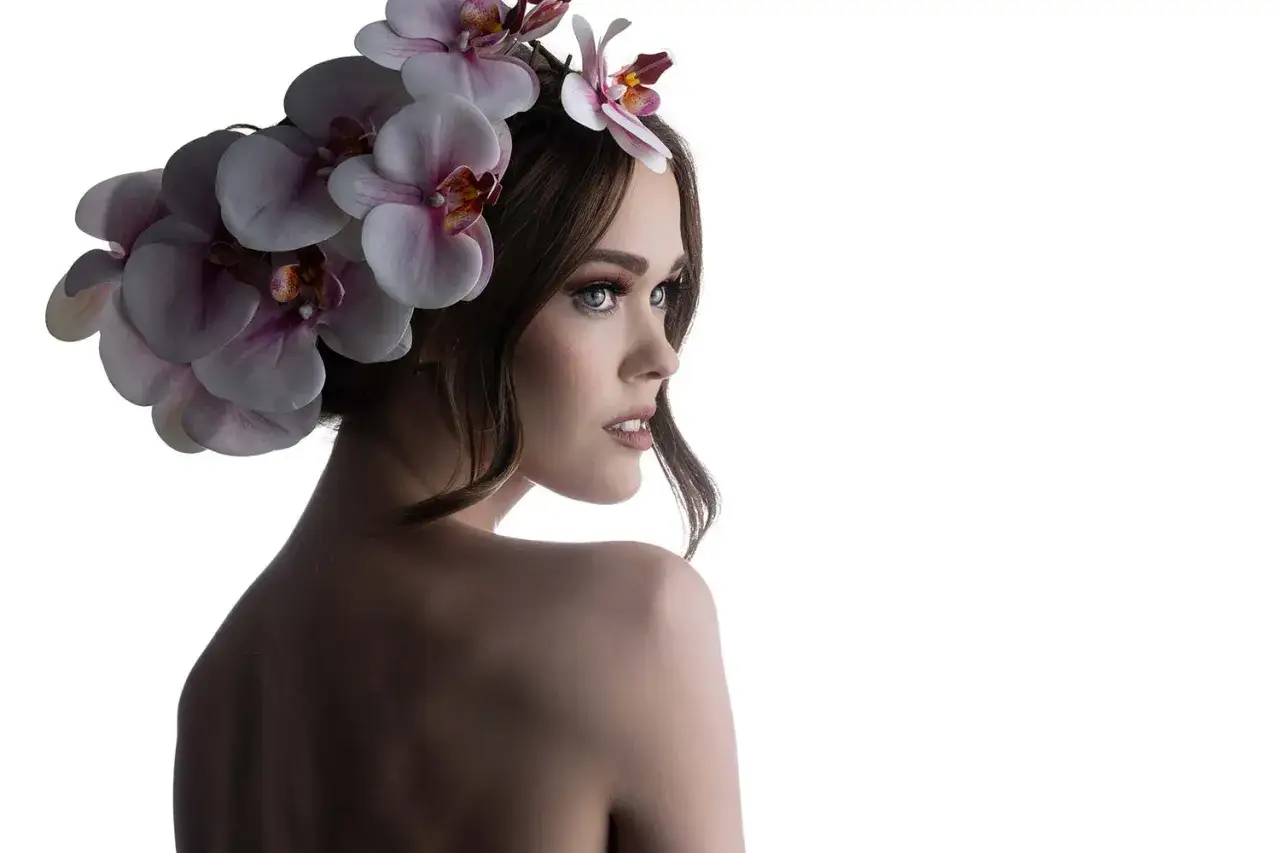 Kobieta z bujną fryzurą z orchidei, odwrócona tyłem, zmysłowe spojrzenie.