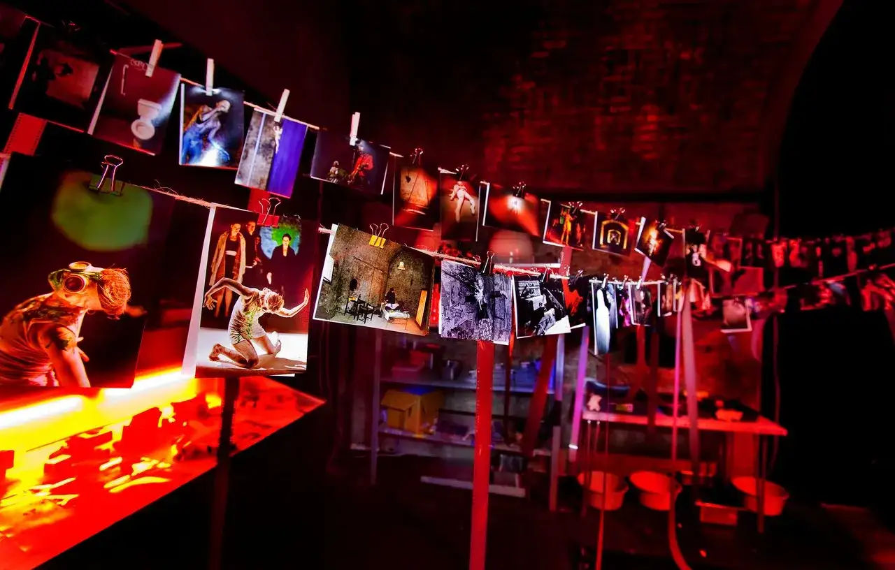 Zdjęcia wiszą na sznurku w ciemni fotograficznej, tworząc artystyczną instalację.