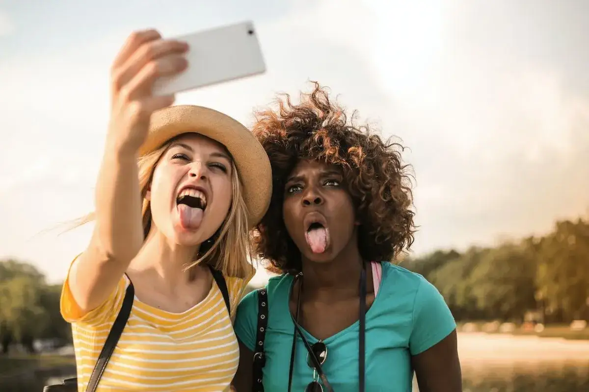 Dwie przyjaciółki robią sobie śmieszne selfie, wystawiając języki. Świetny pomysł na selfie!