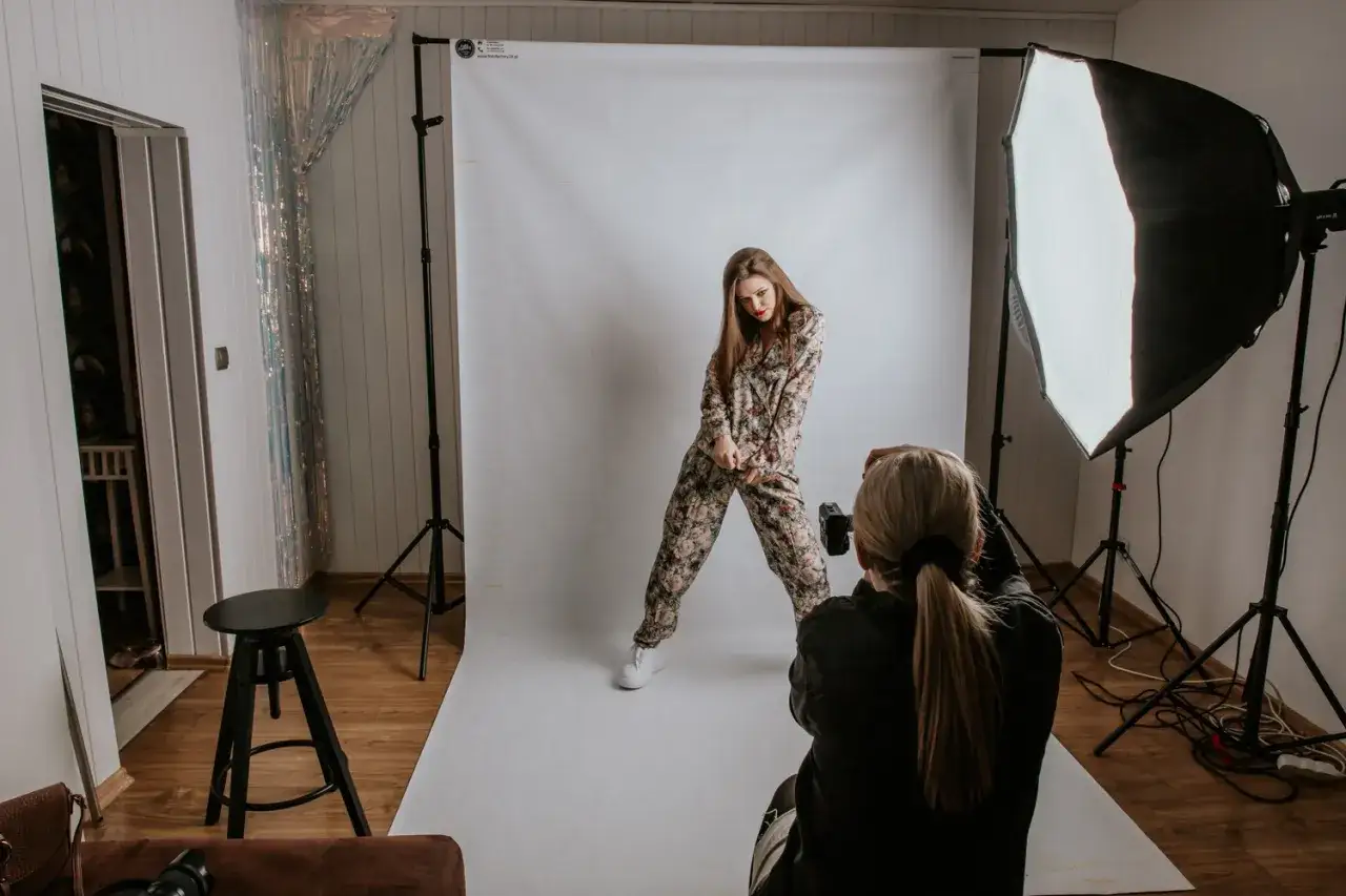 Sesja zdjęciowa w studio. Modelka w kwiecistym kombinezonie pozuje do profesjonalnej fotografii mody i reklamowej.