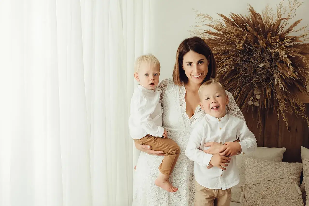 Uśmiechnięta mama z dwoma synami w białych koszulach. Inspirujące sesje zdjęciowe dzieci pomysły na rodzinne wspomnienia.