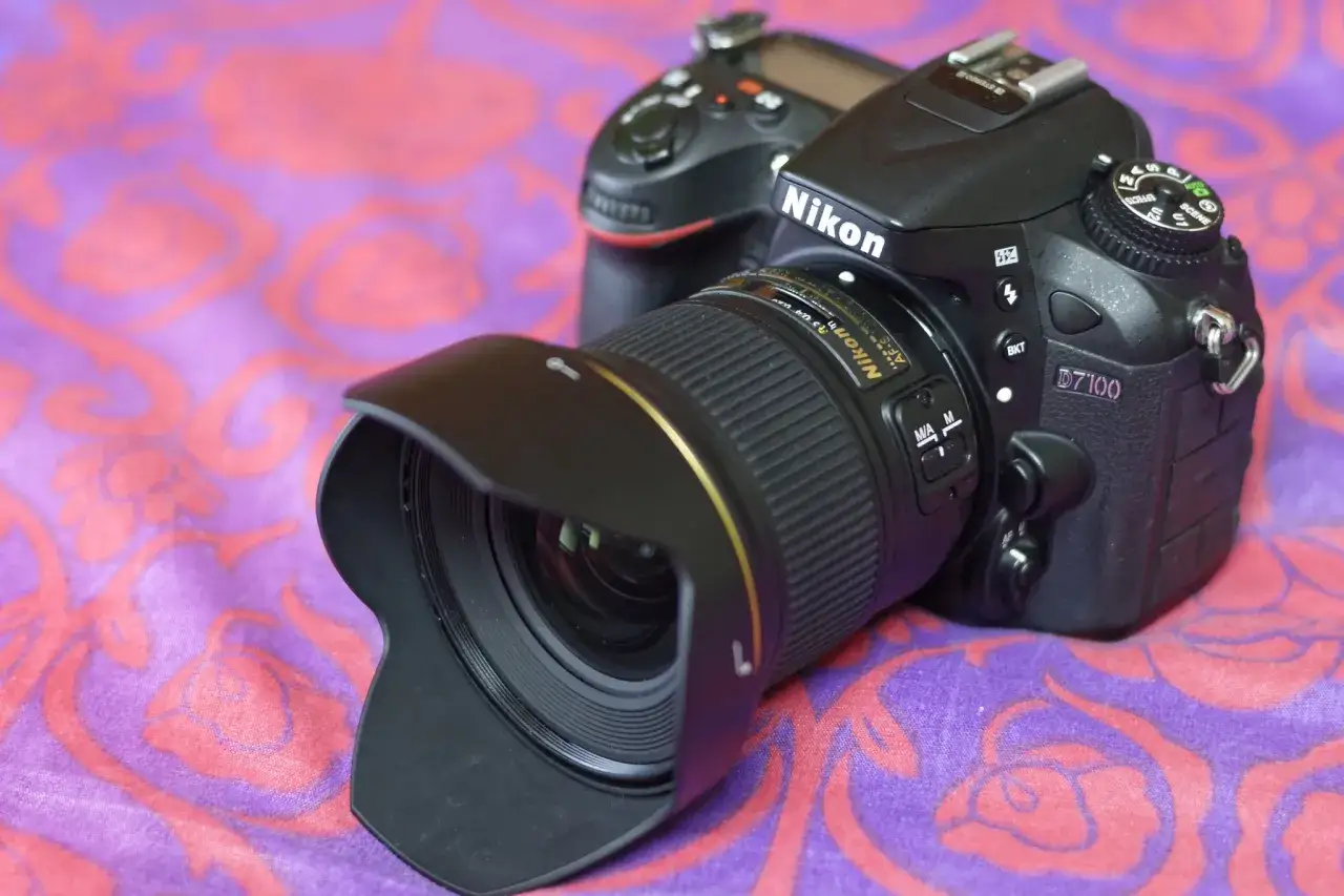 Nikon D7100 z obiektywem AF-S na fioletowym tle z r&oacute;żowymi wzorami. Gotowy do uchwycenia każdej chwili.