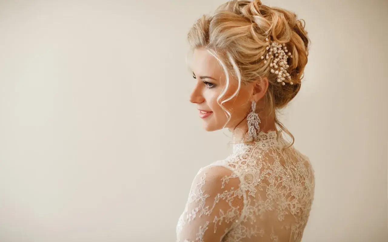 Eleganckie upięcia ślubne z perłami i kryształami, podkreślające urodę panny młodej w koronkowej sukni.