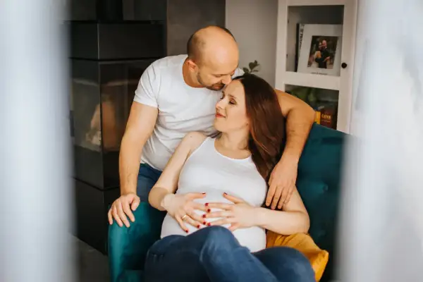 Ciepła, naturalna sesja ciążowa. Przyszli rodzice w objęciach, czułość i oczekiwanie na dziecko.
