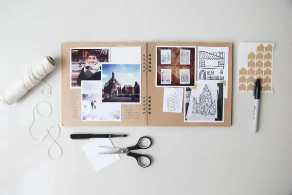 Kreatywne projekty fotograficzne w albumie: zdjęcia, szkice budynków, notatki i akcesoria do tworzenia.