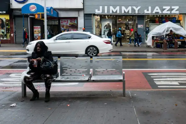 Kobieta siedzi na ławce na ulicy w USA, obok sklepu Jimmy Jazz.