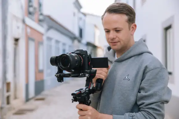 Mężczyzna trzyma stabilizator z korpusem aparatu fotograficznego Sony Alpha 7.