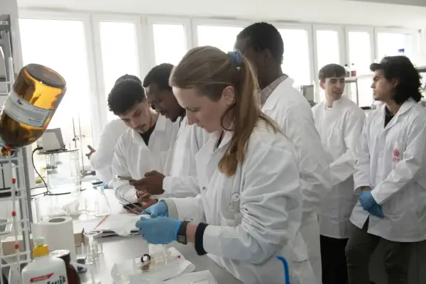 Monika Wanat i studenci w białych fartuchach pracują w laboratorium.