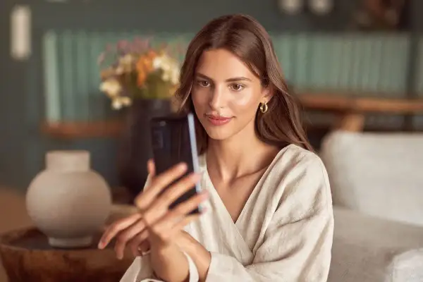 Kobieta robi selfie w lustrze, ale jej twarz jest zasłonięta przez telefon.