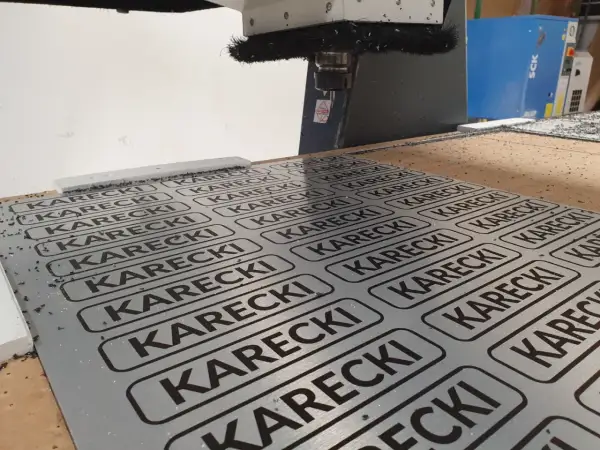 Cięcie CNC na płycie alu dibond z powtarzającym się napisem KARECKI.