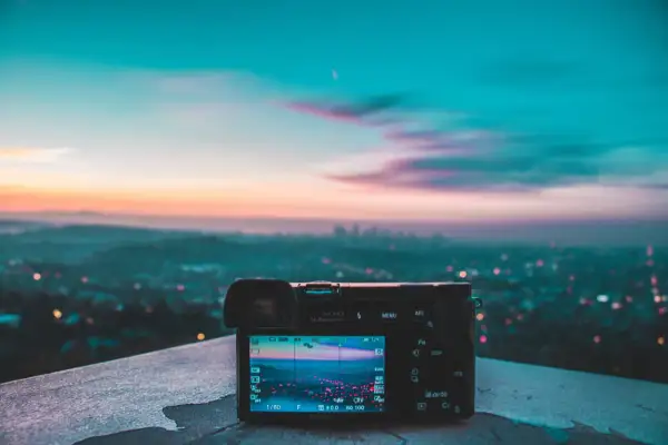 Aparat fotograficzny na tle miasta o zachodzie słońca. Piękne, pastelowe światło zastane maluje niebo, tworząc magiczną atmosferę.