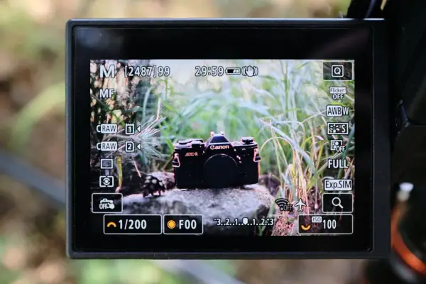 Wyświetlacz aparatu z widokiem na czarny Canon AE-1. Ustawienia aparatu, w tym matryca 1 cal, wskazują na gotowość do fotografowania.