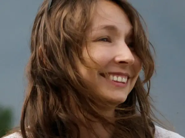 Uśmiechnięta Karolina Jonderko z rozwianymi włosami na tle nieba.